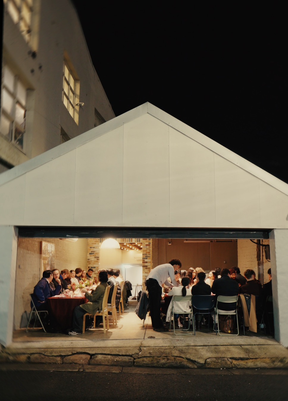 The restaurant at night, with guests gathered around warmly lit dinner tables